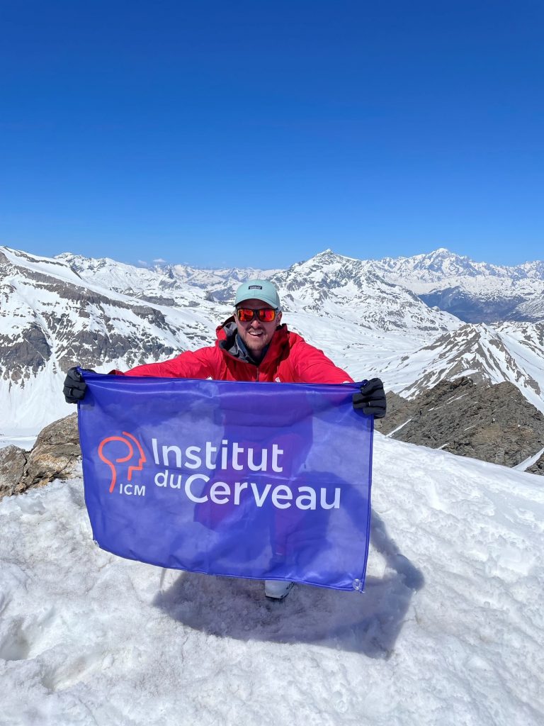 Le passionné de montagne Antoine Bovyn tient le fanion de l'Institut du Cerveau